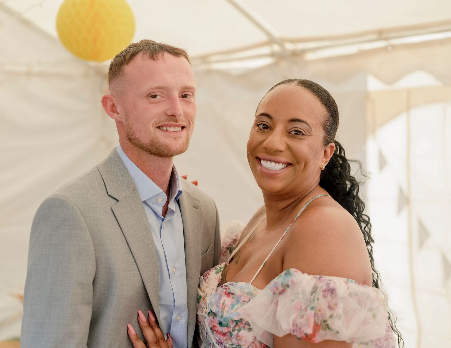 Wedding couple sharing a romantic moment under a white tent at their reception.