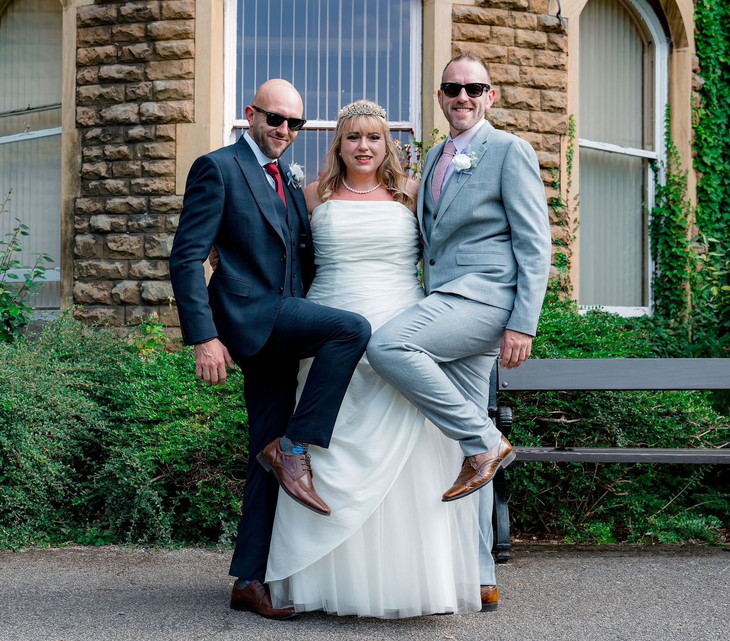 Celebratory group poses in front of stone wall with windows.