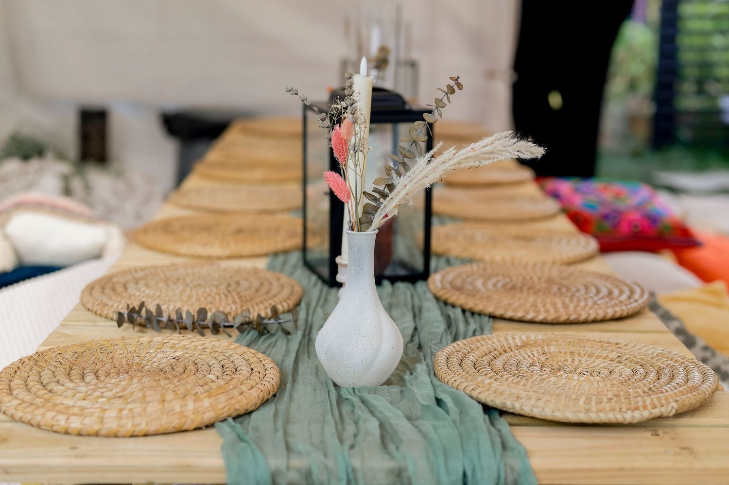 Rustic woven rattan charger plates arranged on a turquoise tablecloth for an outdoor dining setting.