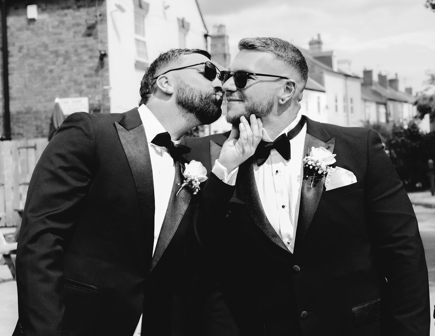 Black and white portrait of groomsmen in formal attire standing together.