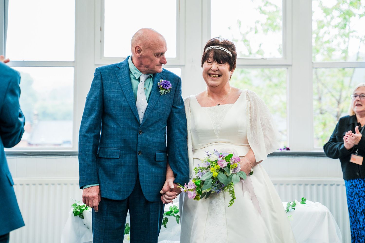 A couple shares a joyful moment during their wedding ceremony in a bright, window-lit venue.