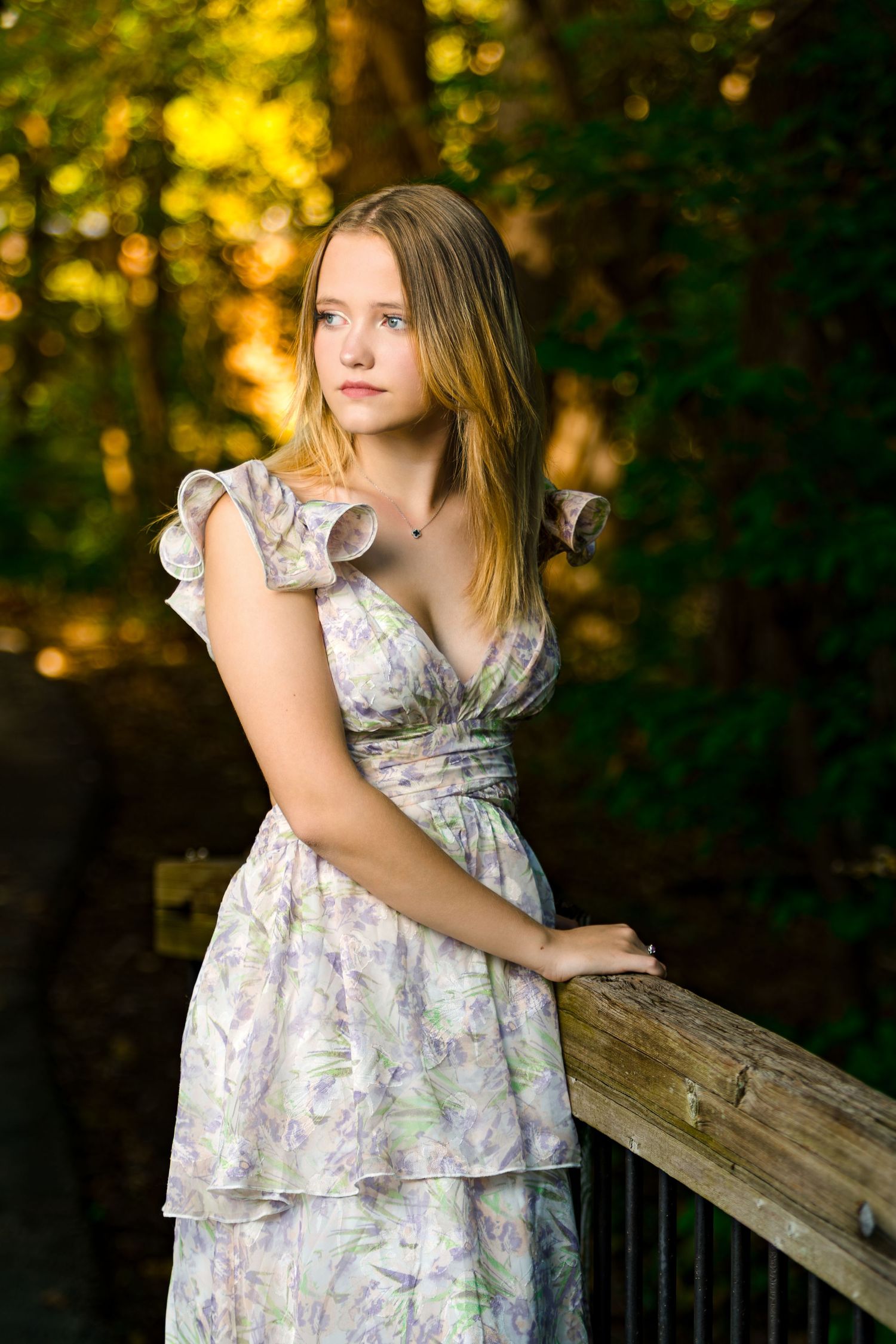 A floral sundress with ruffled cap sleeves photographed at sunset against a golden bokeh forest background.
