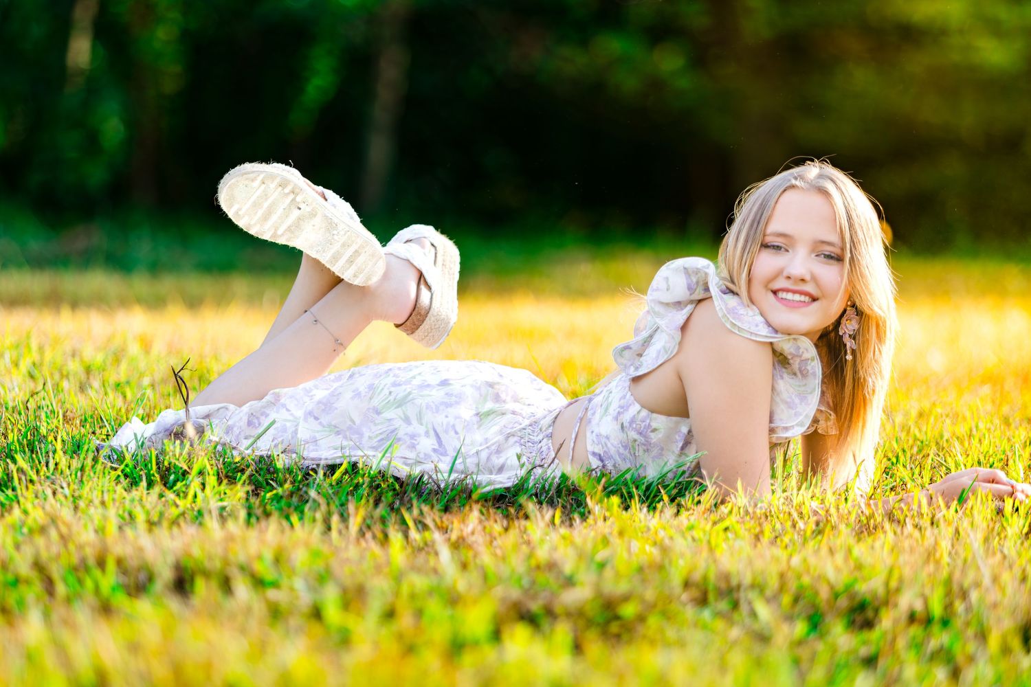 Person lying in a lush green meadow during golden hour with sunlight creating a warm, dreamy atmosphere.