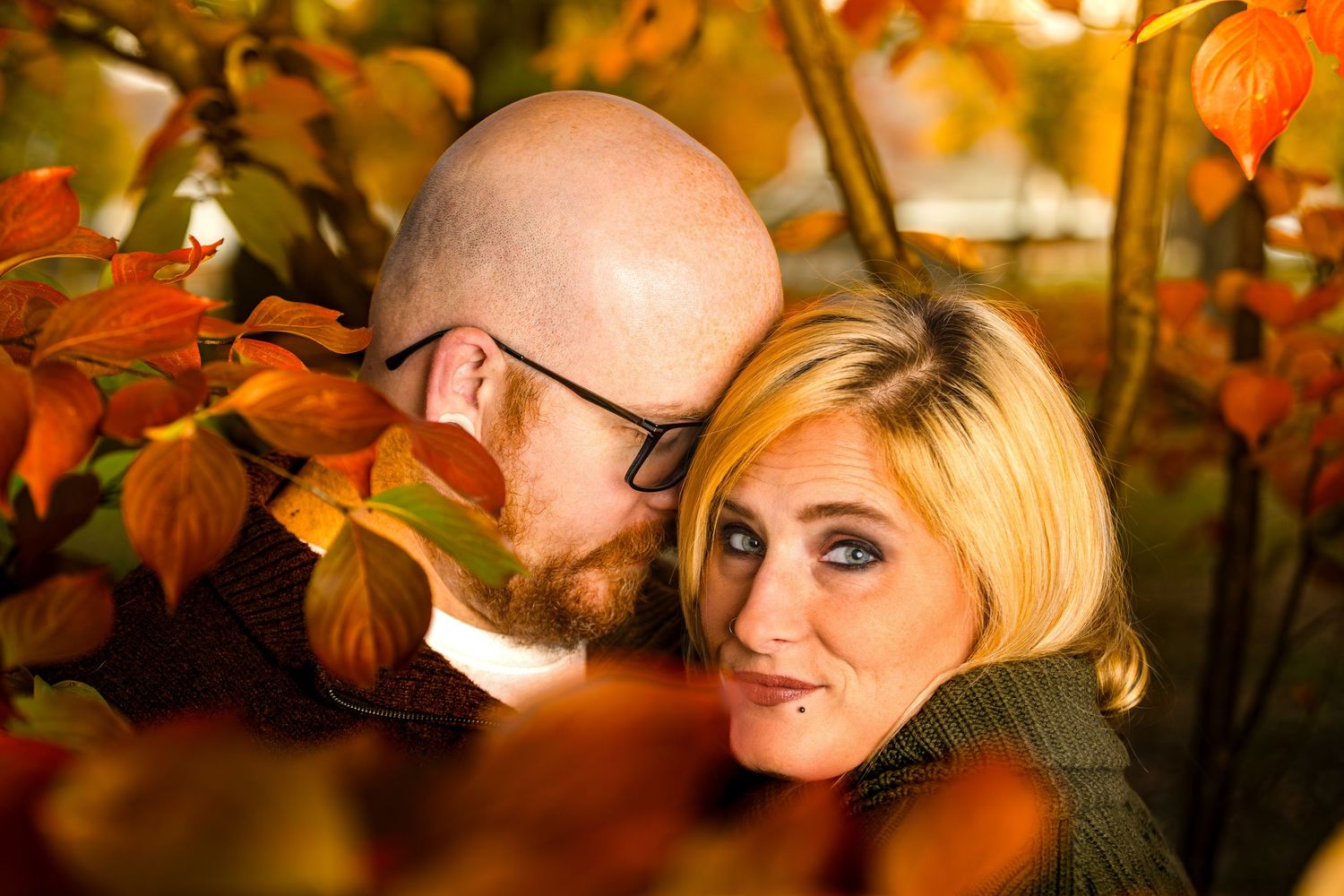 Two people share a romantic moment surrounded by warm autumn decor and twinkling lights at a wedding reception.