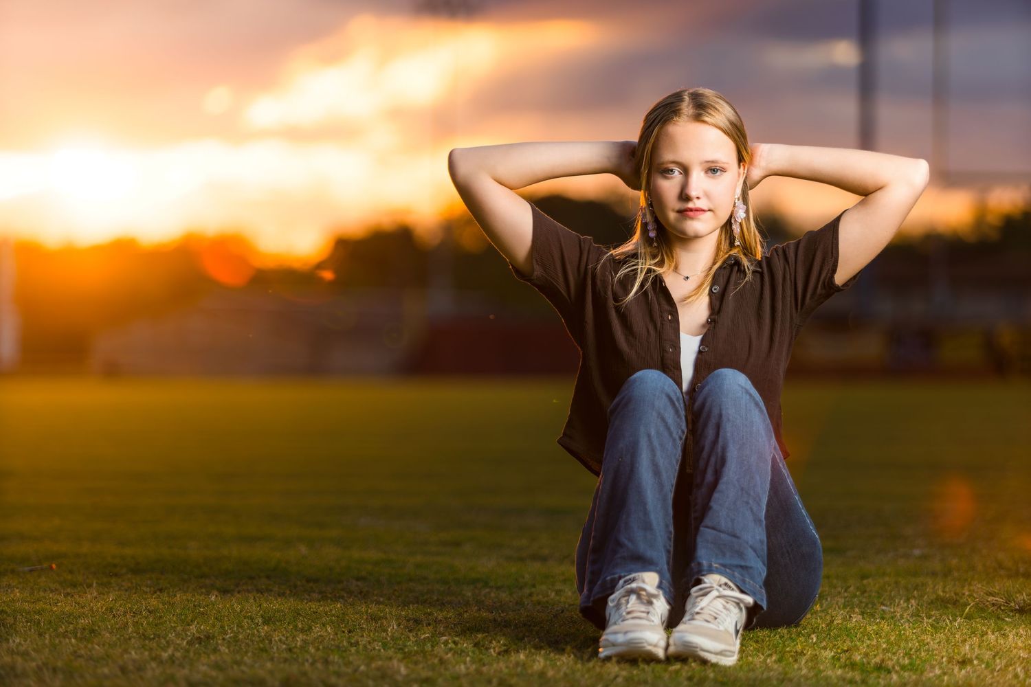 A silhouetted figure performs sit-ups during a vibrant sunset over a grassy field, creating a dramatic orange backdrop.