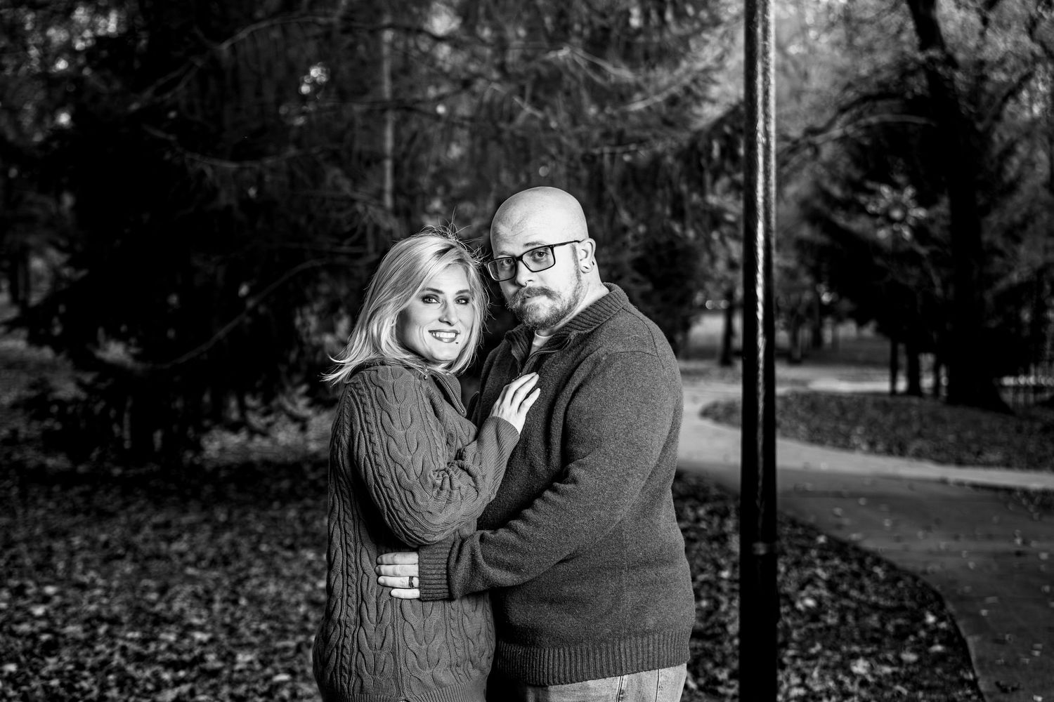 A romantic black and white photo series showing a couple embracing in a park setting during autumn.