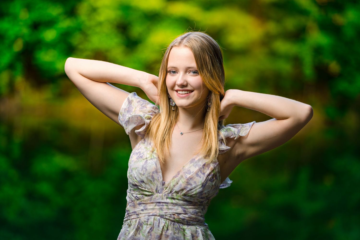 A joyful figure in a floral dress poses playfully in a lush green forest setting during a bright summer day.
