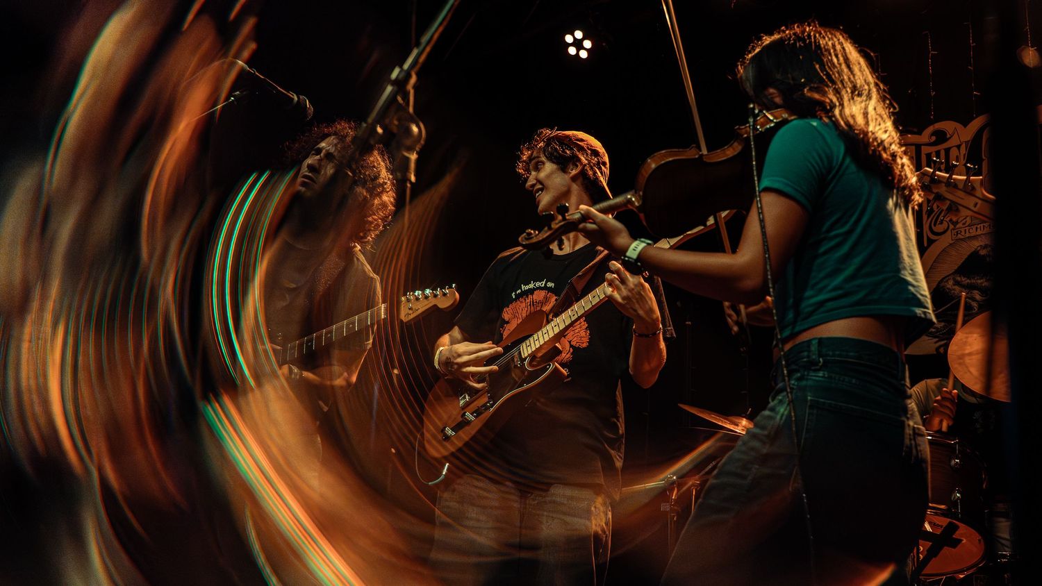 Concert performers create dynamic energy on stage with swirling motion blur and dramatic lighting effects.