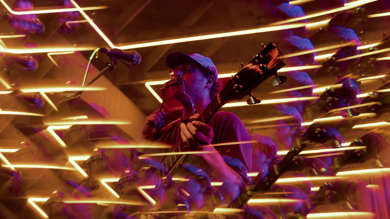 Purple and yellow light beams streak across a dark space creating a dynamic pattern of illumination.