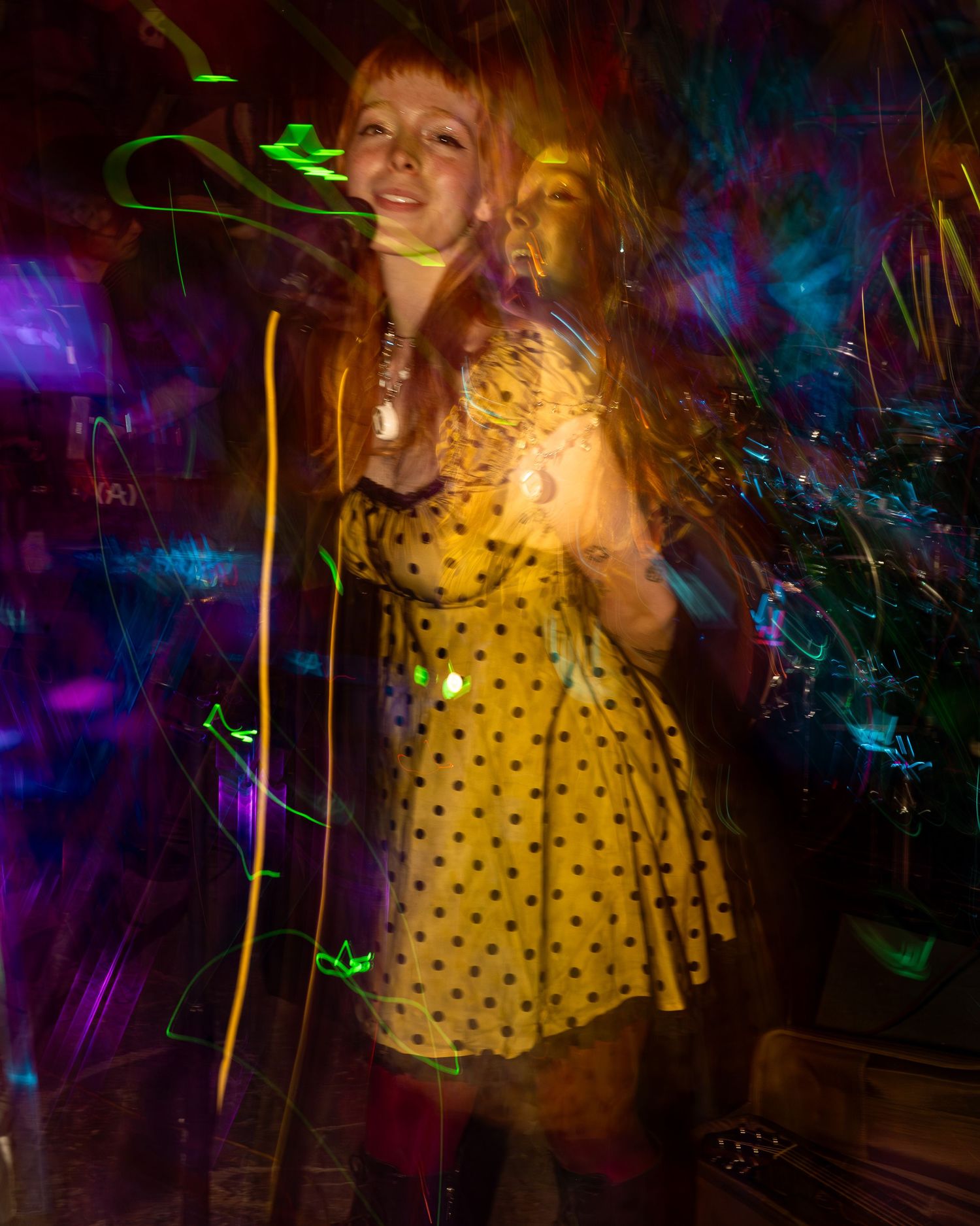 Concert performance with psychedelic light trails and a polka dot dress creating dynamic visual effects.