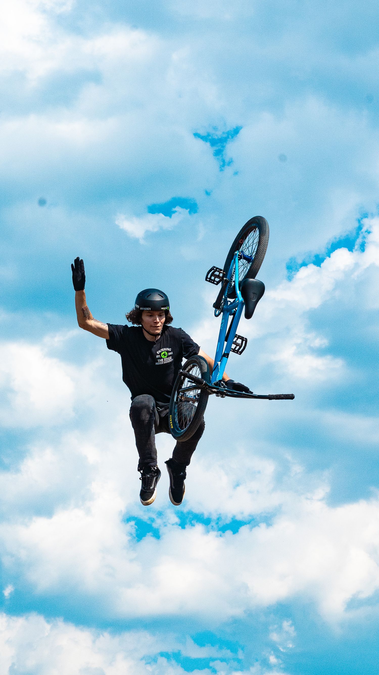 BMX rider performs aerial trick separating from bike against cloudy sky.