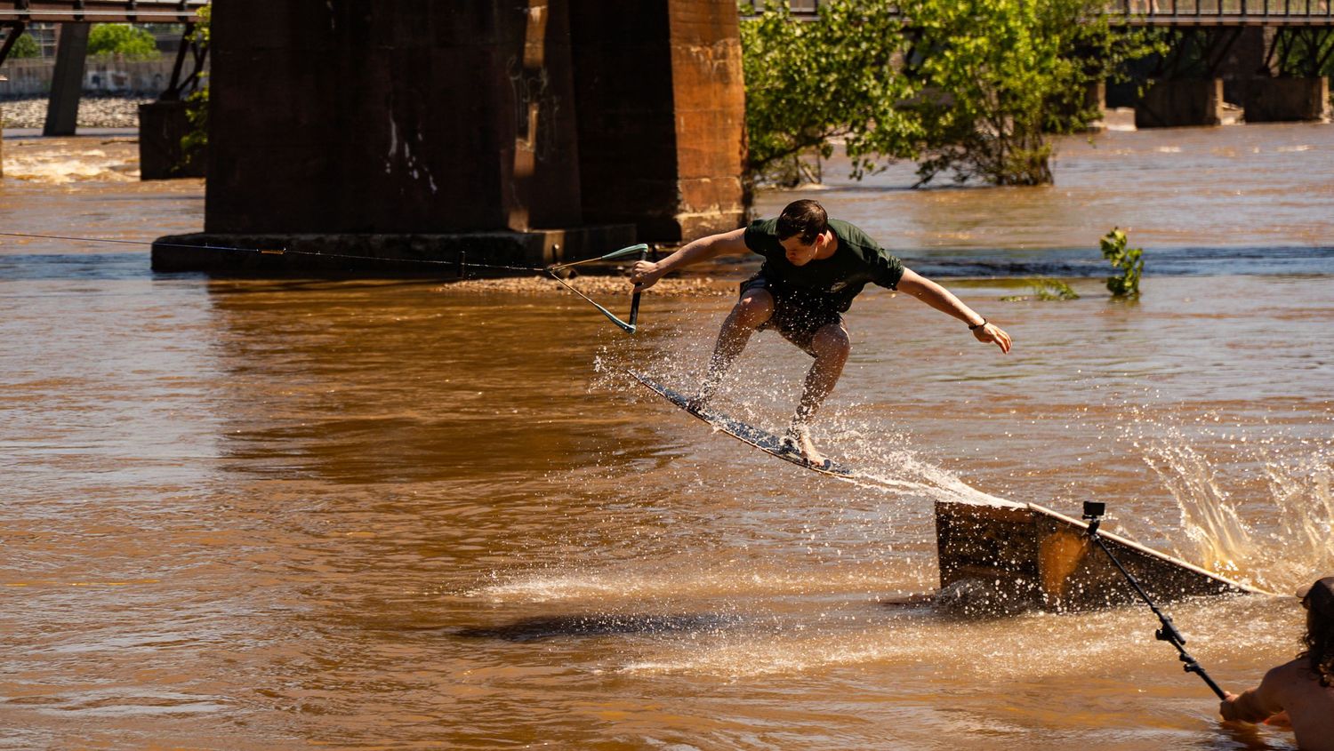 BMX riders splashing through flood waters while performing tricks.