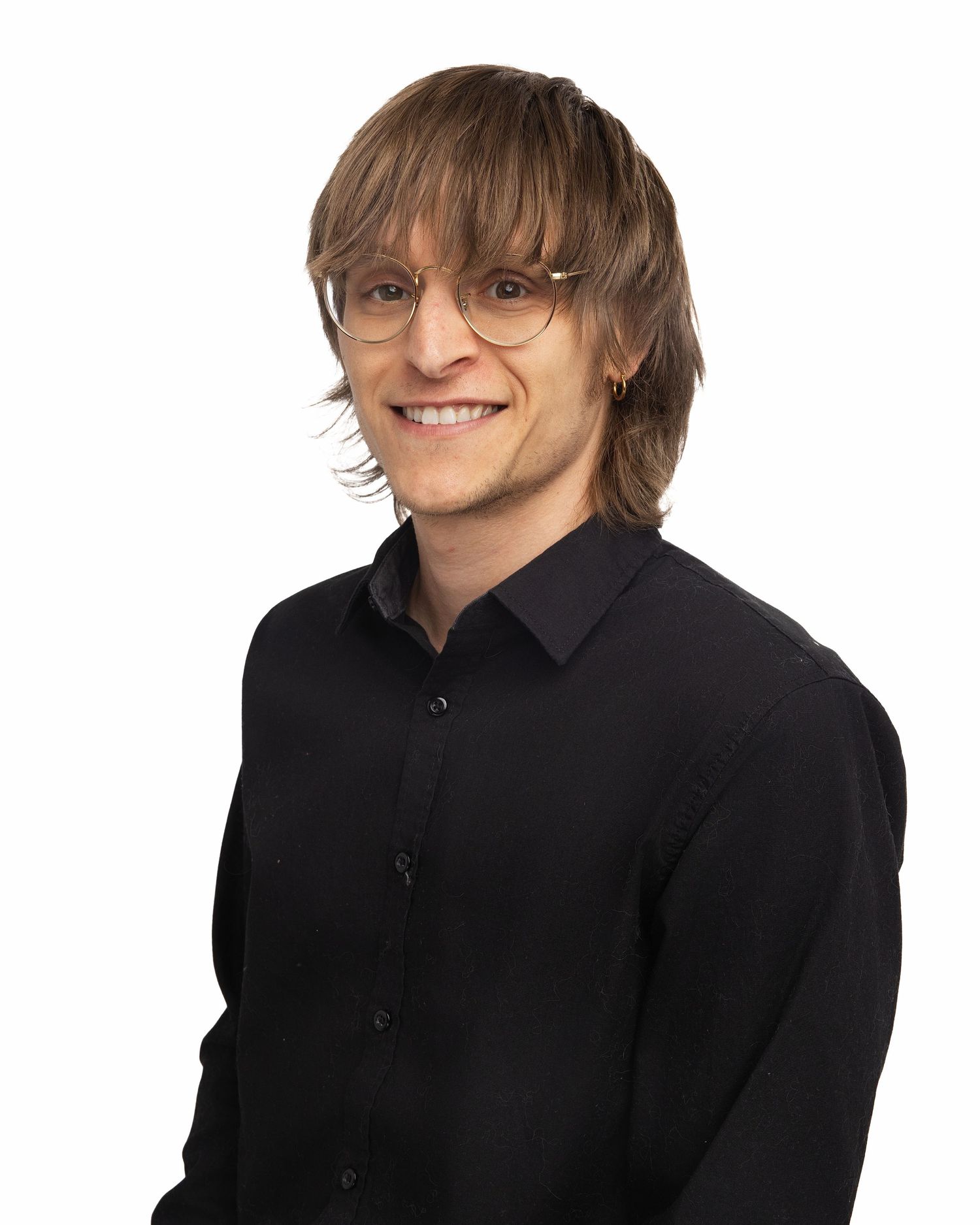 Casual portrait of someone in a black button-down shirt wearing glasses with layered hair.