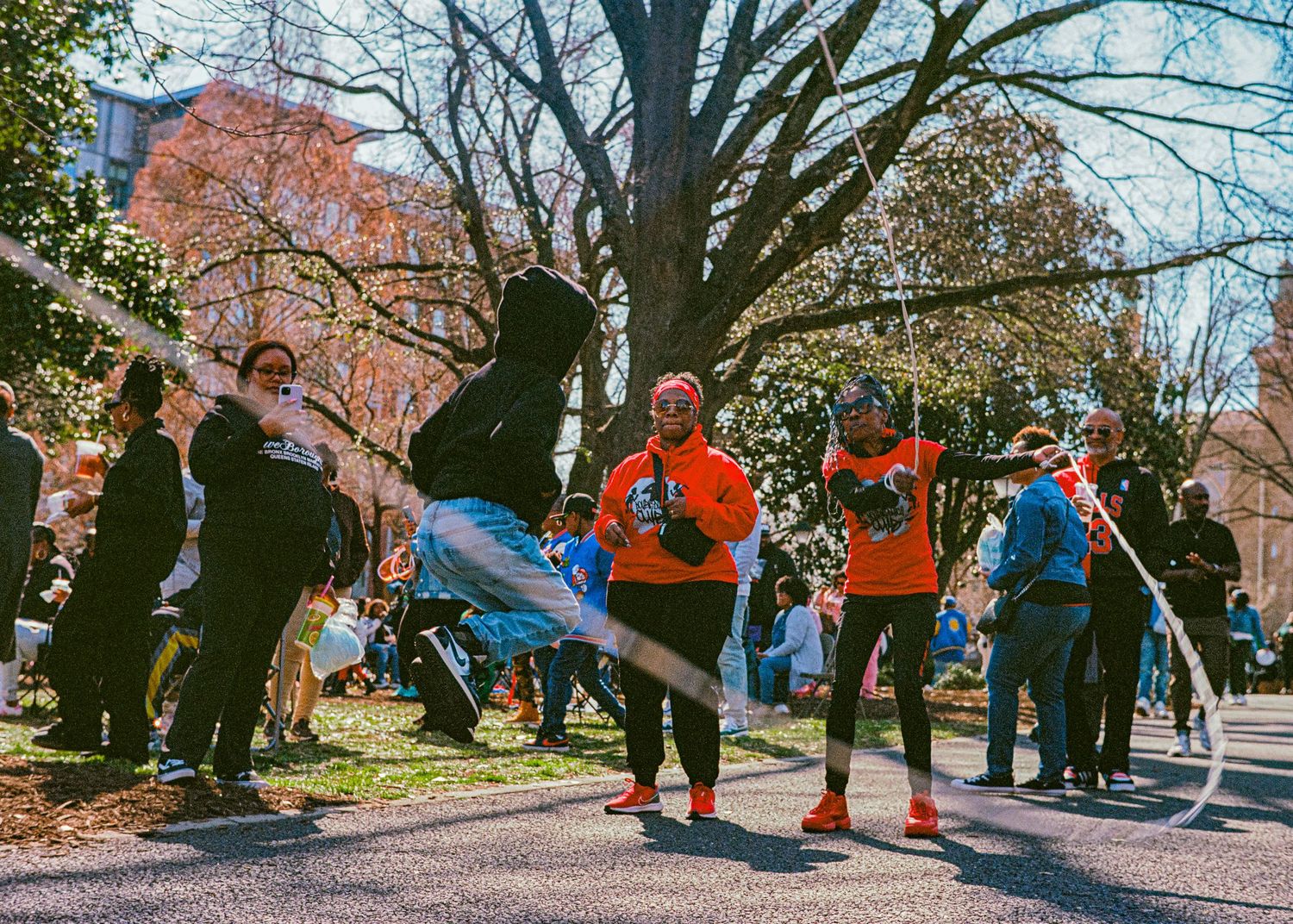 A group of runners warming up together outdoors on an autumn day with colorful fall trees in the background.