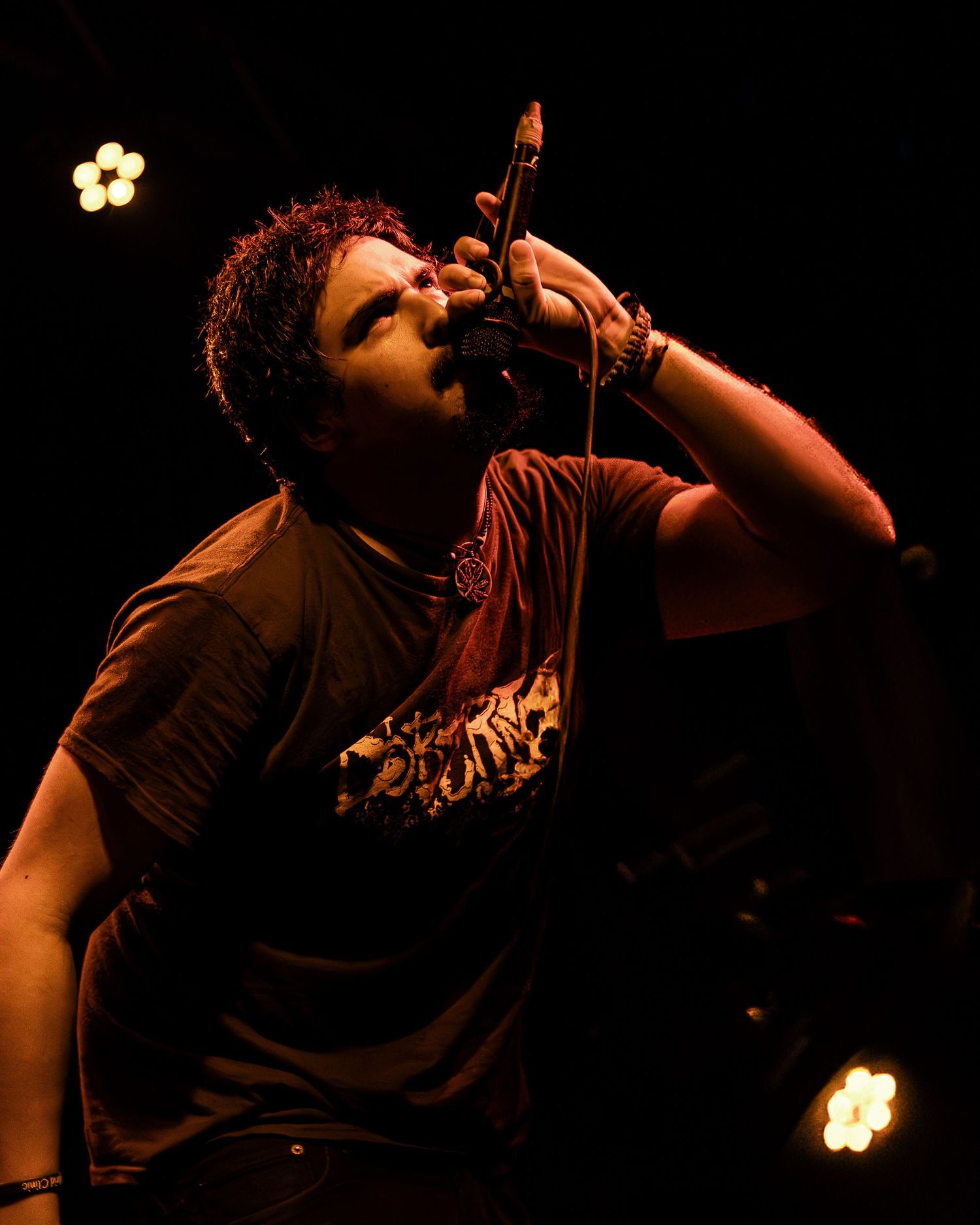 A singer performs passionately on stage in dramatic lighting against a dark background.