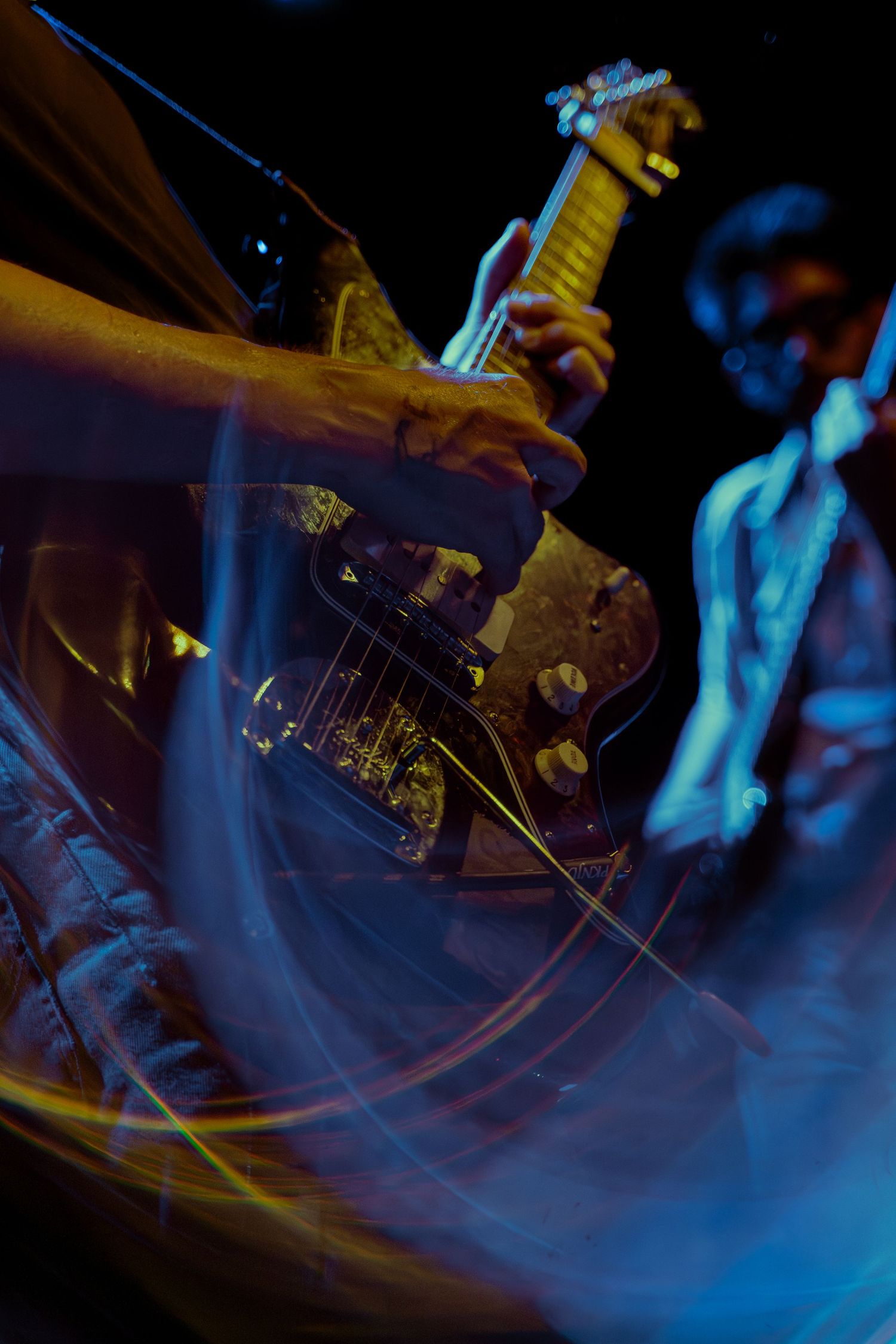 Motion-blurred action shots of a guitar performance with blue lighting create an energetic concert atmosphere.
