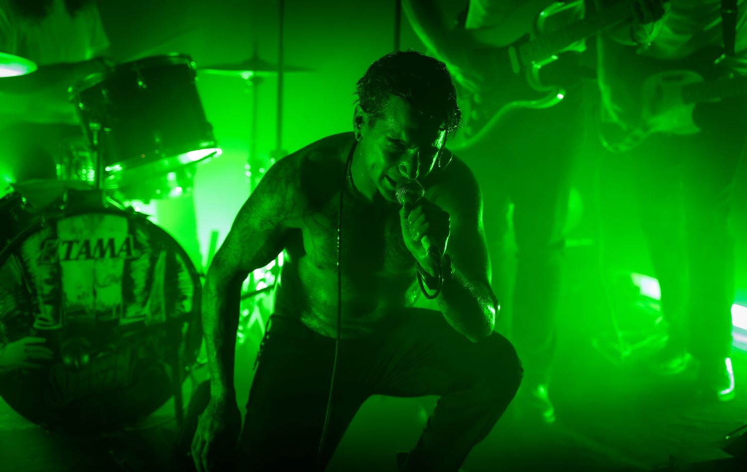 Concert stage bathed in bright green lighting effects during an intense musical performance.
