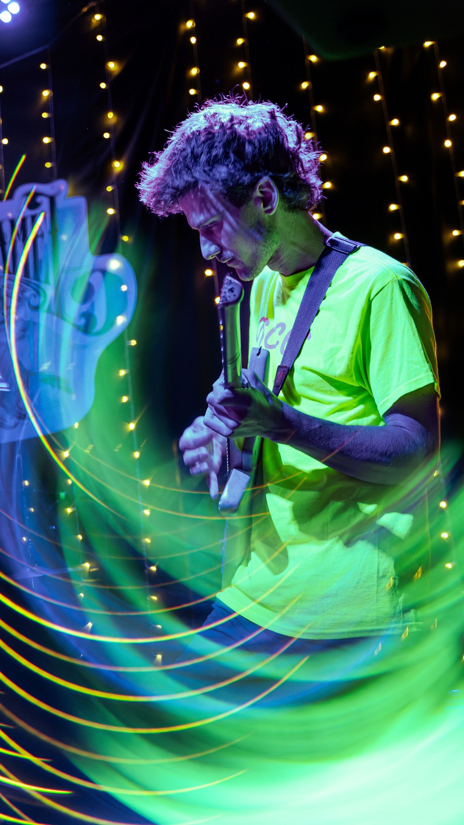 Dynamic long exposure shot featuring neon green light trails against a dark background with golden twinkle lights.