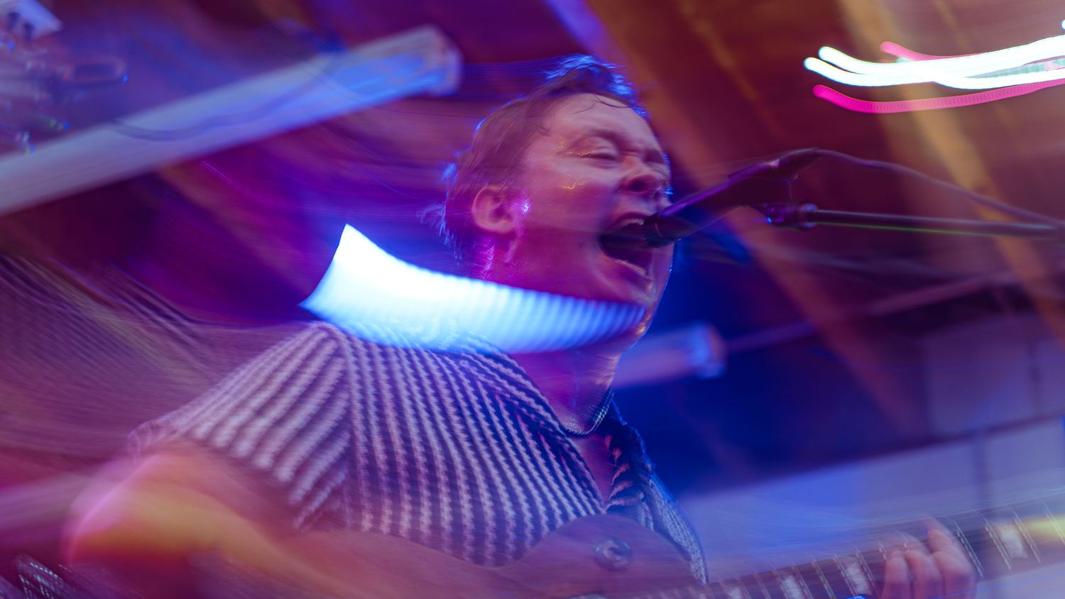 Concert performer singing with dramatic blue neon lighting effect in motion blur.