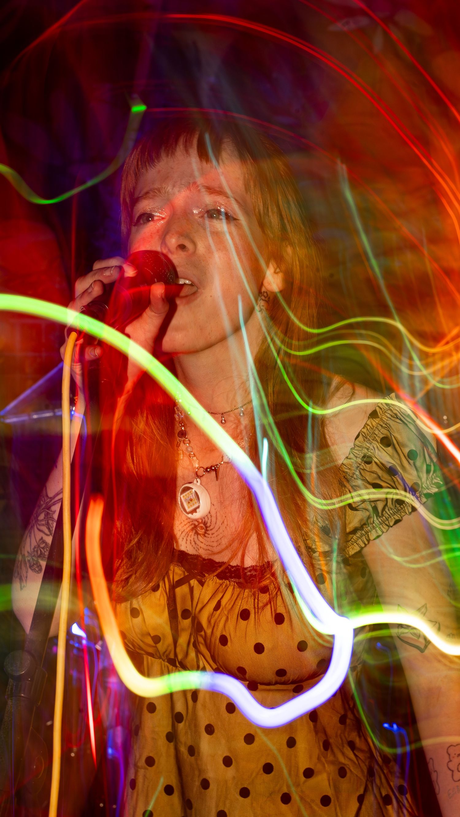 Performance captured with neon light trails and motion blur effects in red and green.