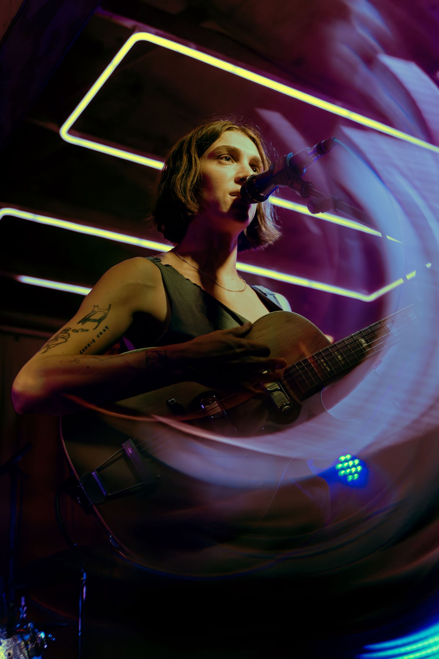 A musician performs on stage with multiple motion-blurred images showing dramatic movement in purple and blue lighting.