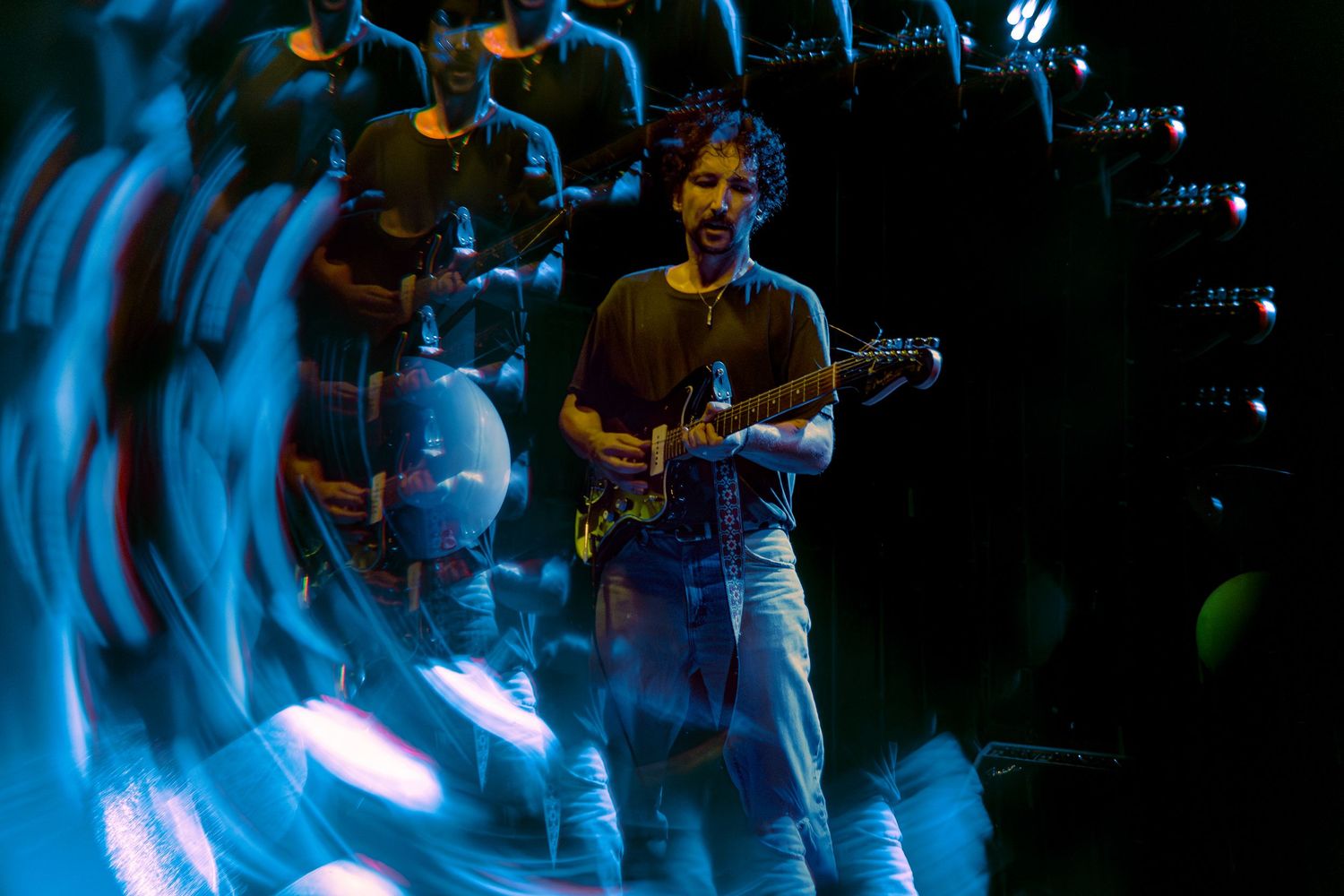 Person performing on a dark stage illuminated by blue spotlights during a musical performance.