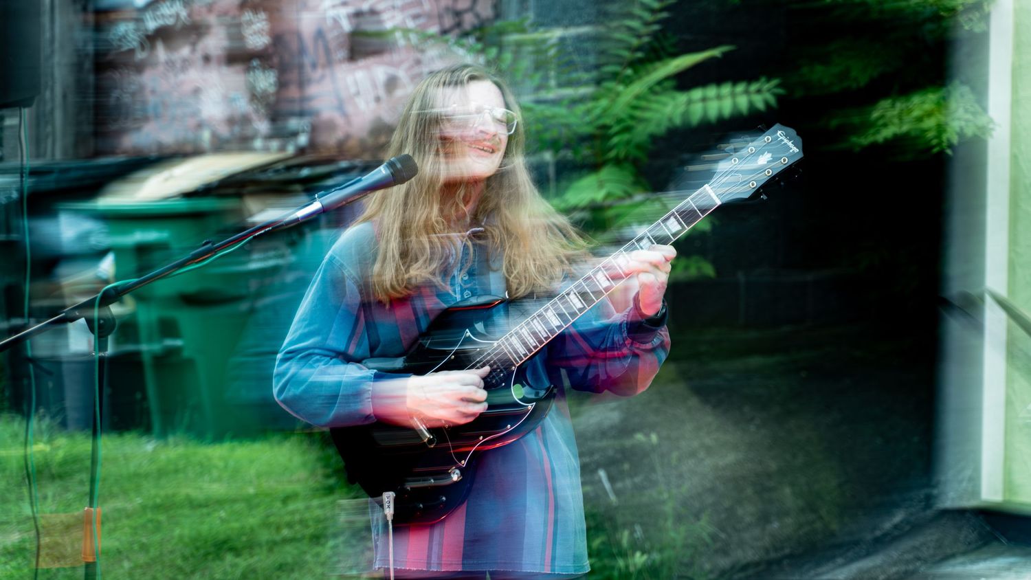 Abstract motion-blurred photograph of musicians performing with green lighting effects.