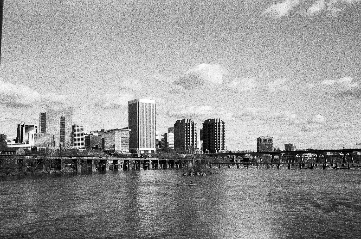 Panoramic black and white skyline view of a waterfront city with tall buildings.