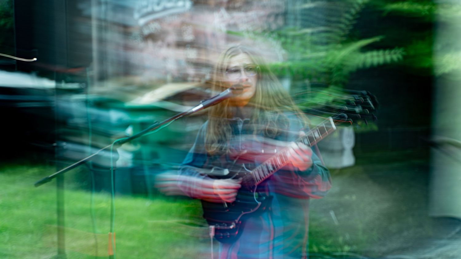 Abstract long exposure photograph of musician performing with green and blue motion trails.