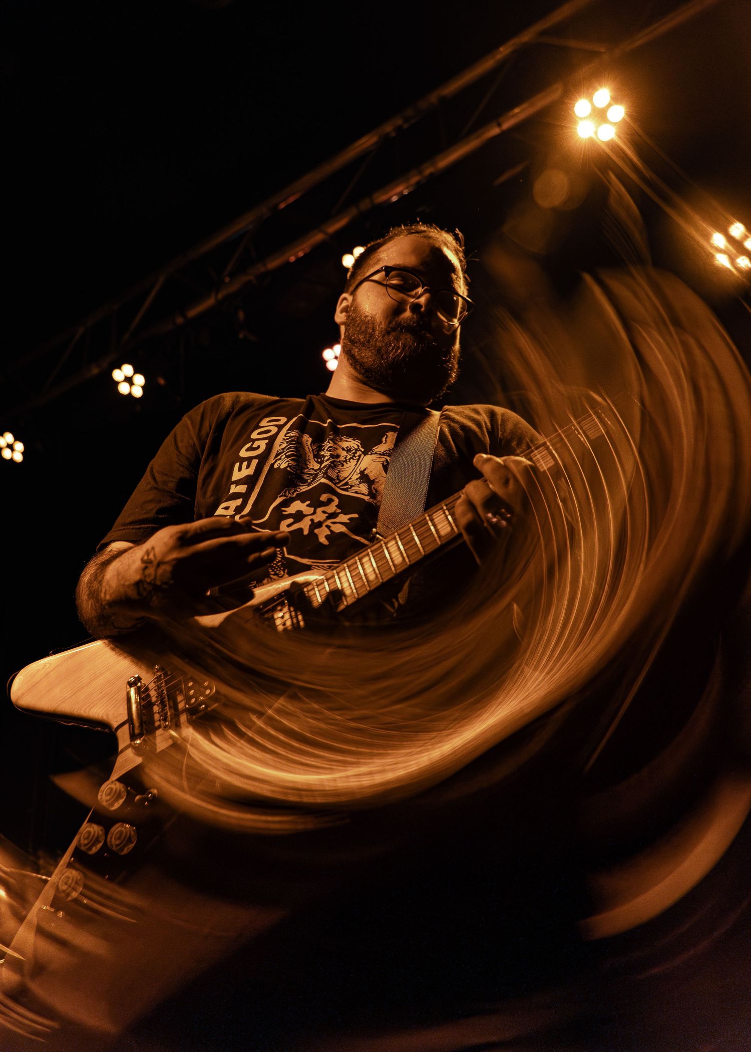 Musician performing on stage at night with dramatic motion blur effect and warm lighting creating swirling patterns.