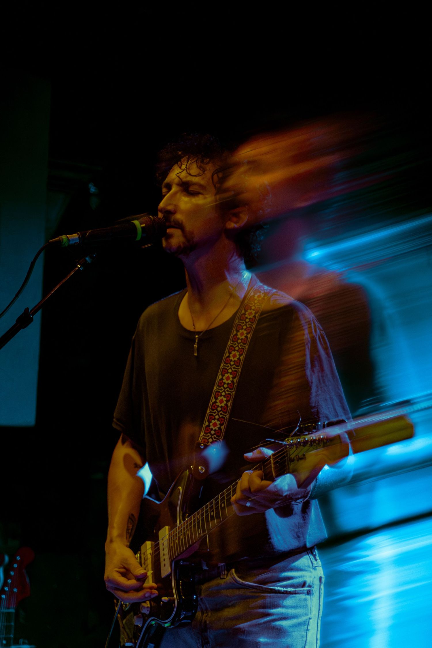 Multiple exposure shot of guitarist performing on stage with dramatic blue lighting effects.