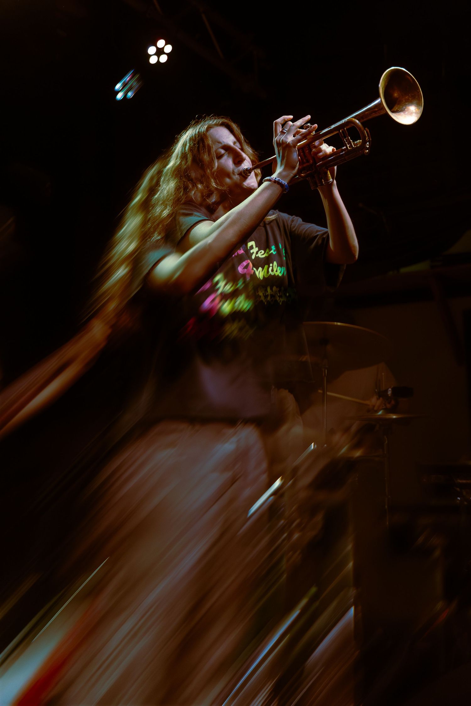 A sequence of dark and moody concert photos showing a trumpet player performing on stage in dramatic lighting.