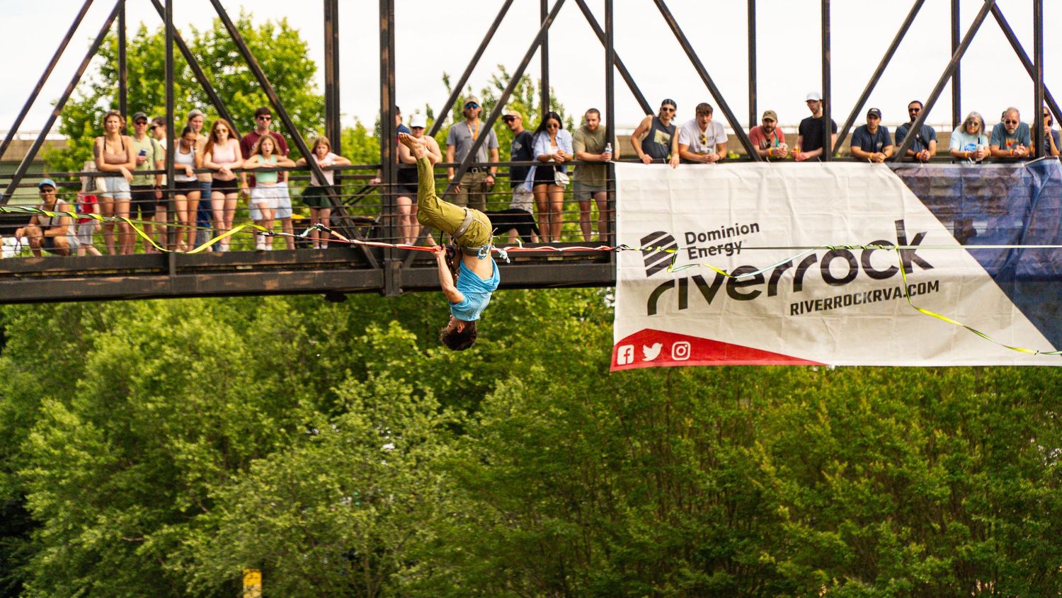 Event crowd watches BMX performance from grassy slopes at outdoor venue.
