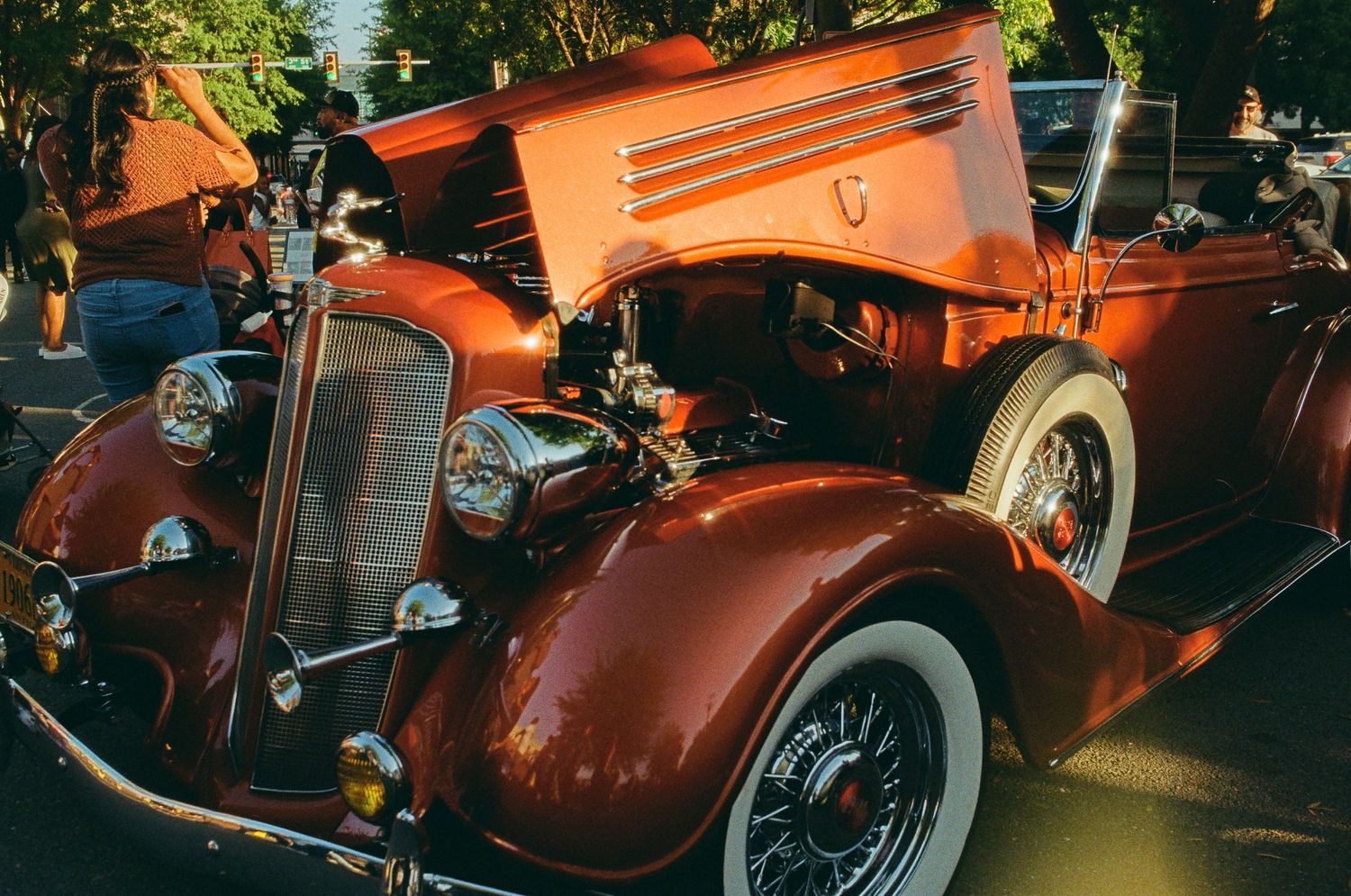 Vintage orange-colored car photographed at sunset with dramatic lighting.