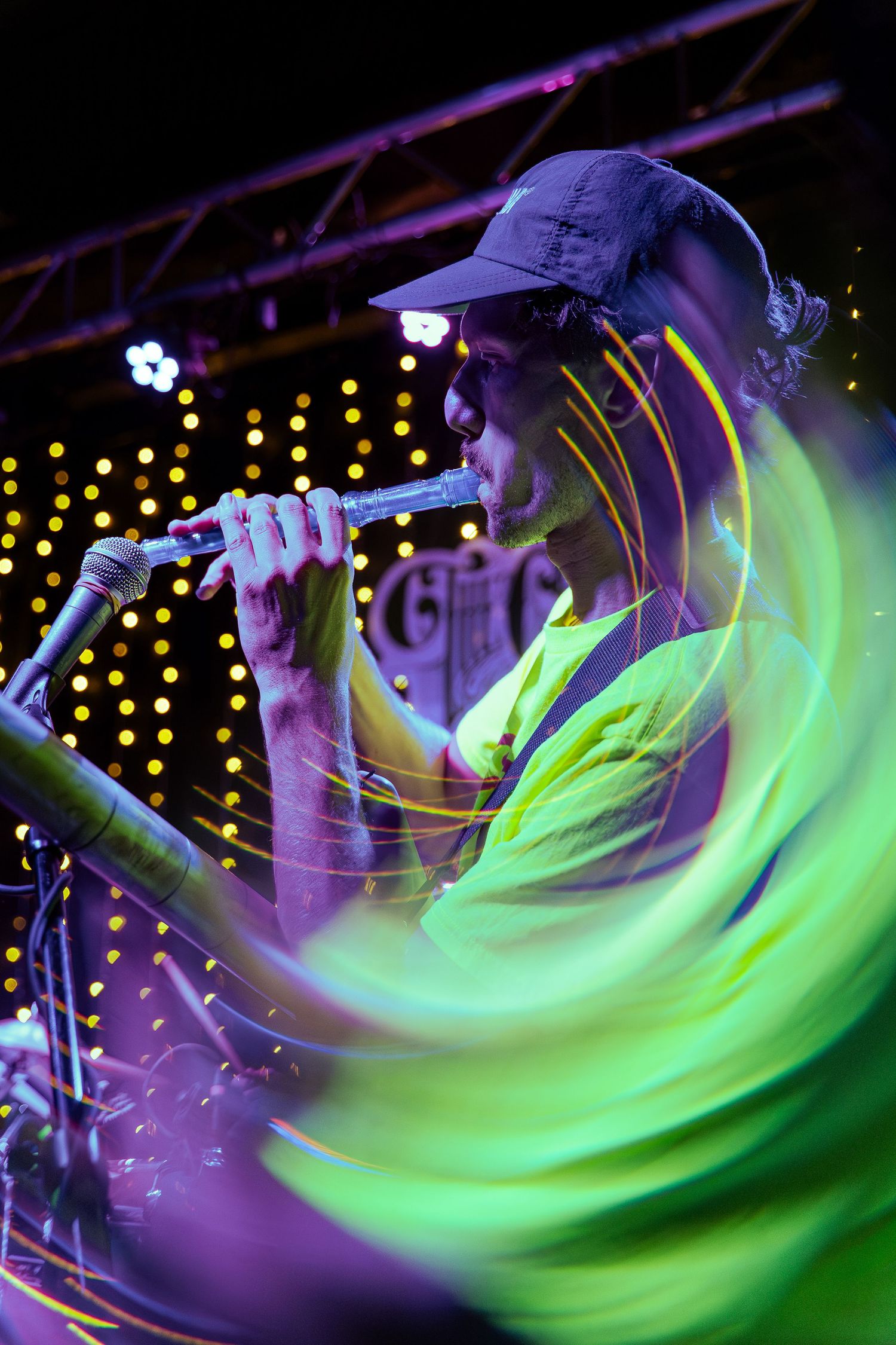 Long exposure photograph shows swirling neon green and purple light trails during a nighttime performance.