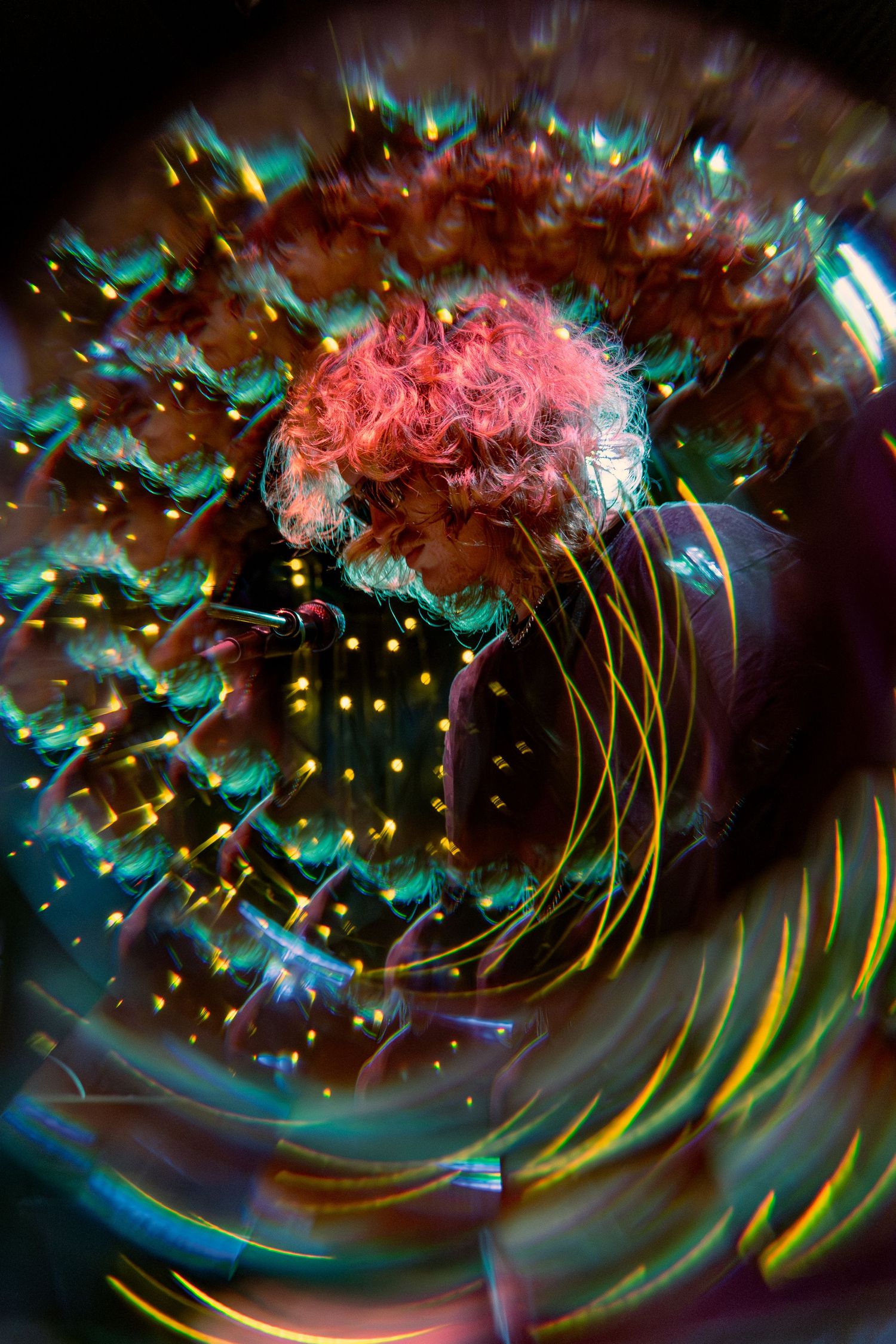 Abstract light painting features pink and green swirling patterns with yellow streaks against a dark background.