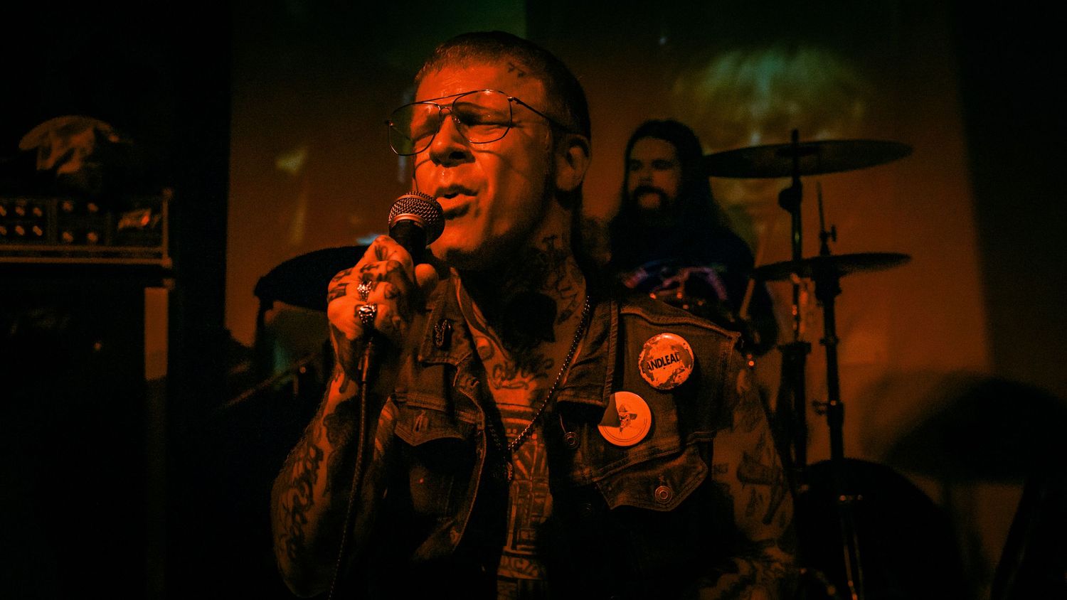 Close-up concert performance with dramatic red and orange stage lighting effects.