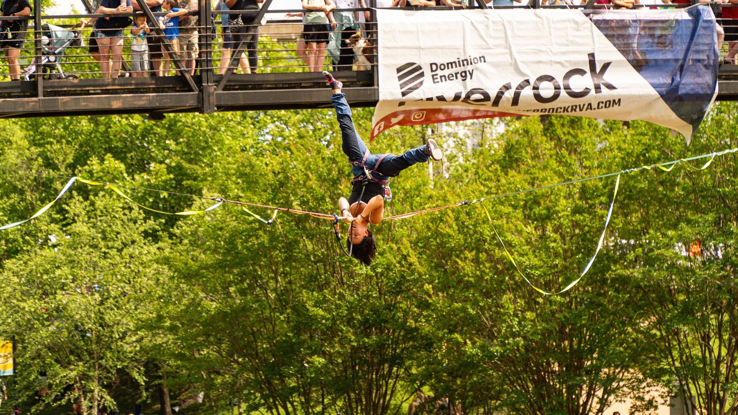 Spectators watch intense BMX stunts from grassy hillside during outdoor event.