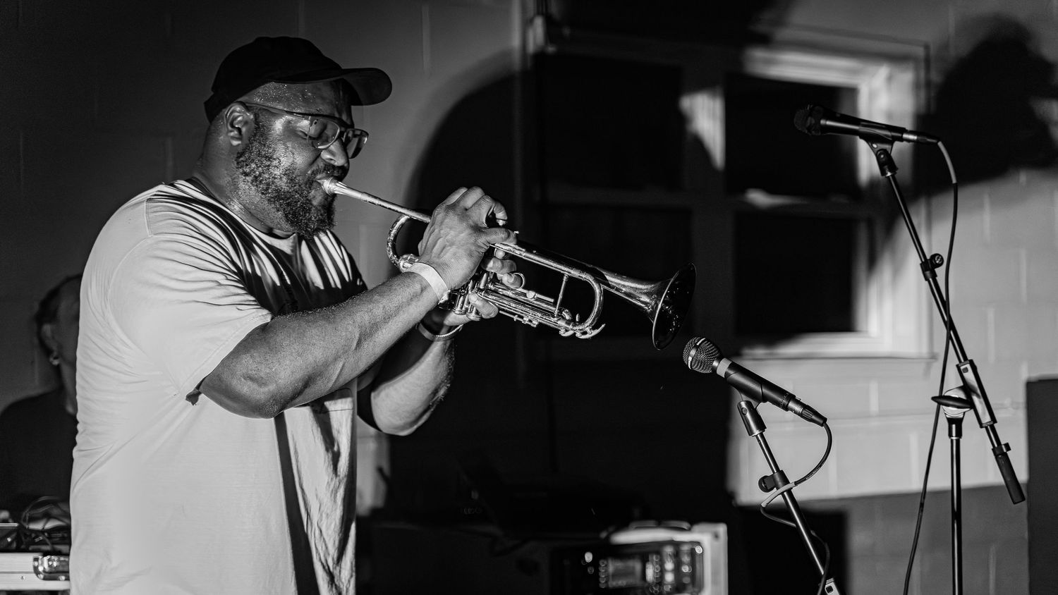 Black and white sequence of a musician performing with a trumpet in dramatic lighting.