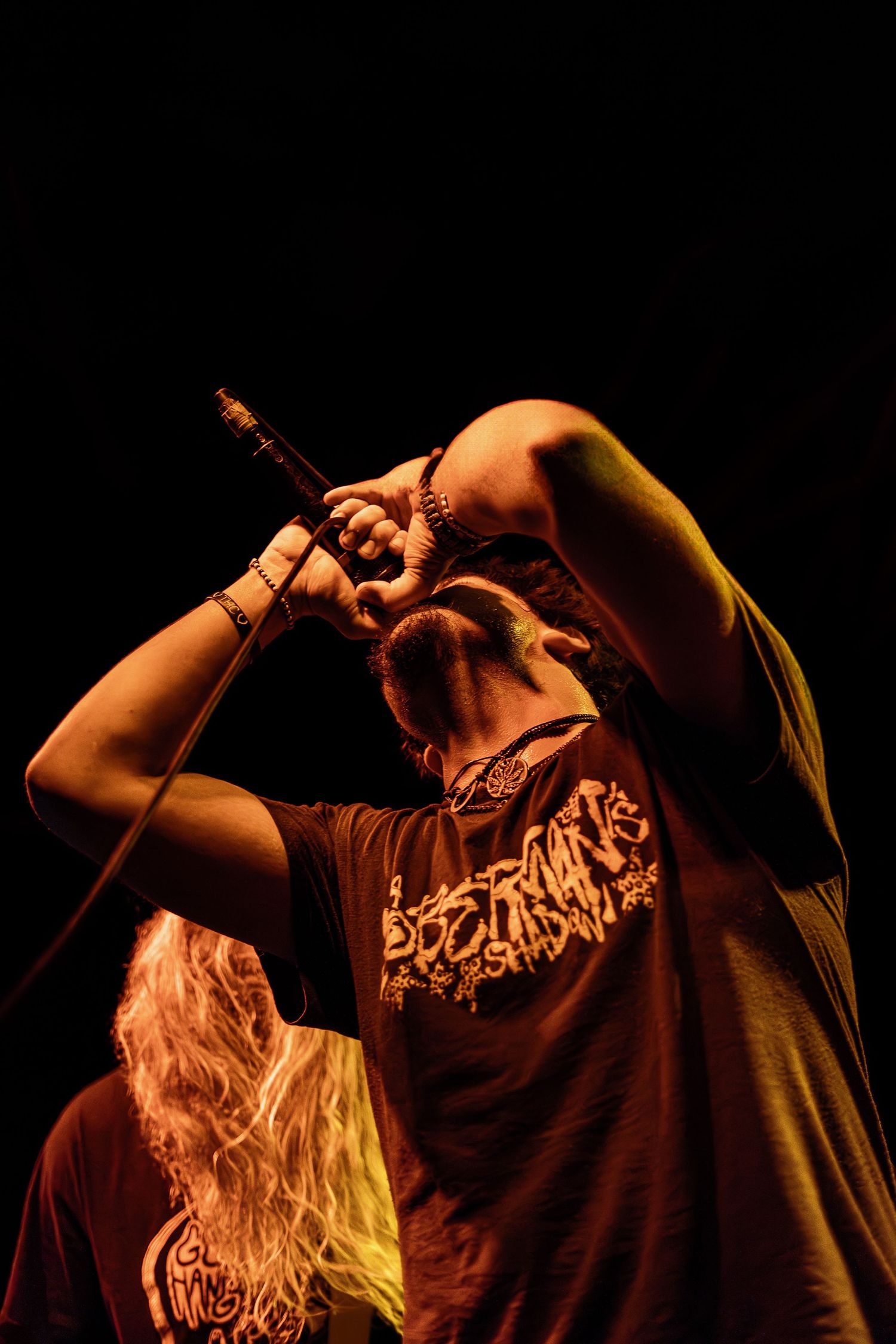 Dramatic silhouette of a performer singing intensely on stage with orange and yellow lighting against a dark background.