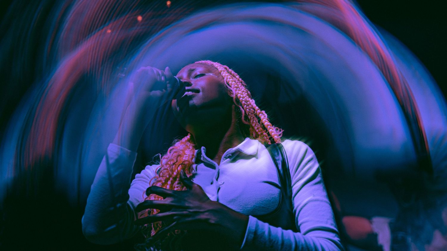 A performer on stage dances energetically in dynamic lighting with multiple exposure effect creating a motion blur trail.