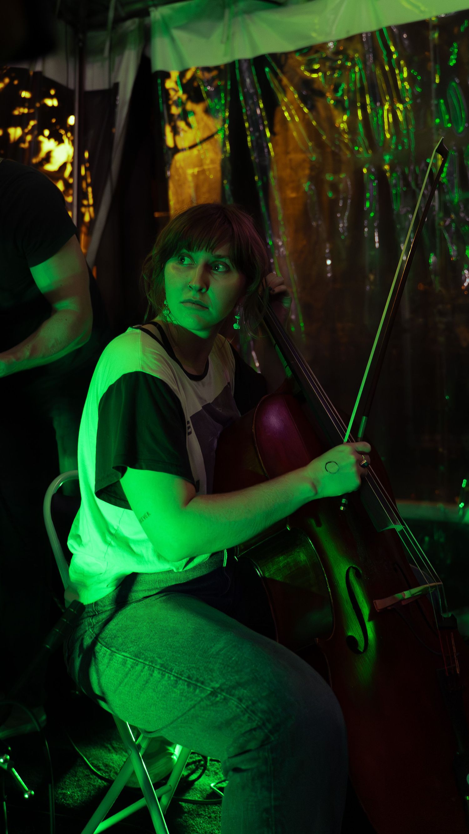 In green lighting, someone plays the steel string instrument tapping the strings in a unique performance style.
