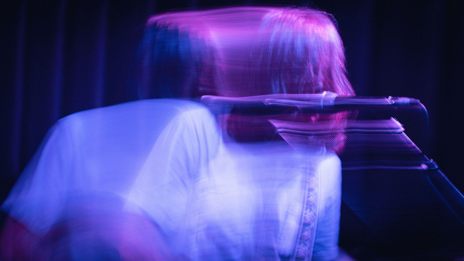 Abstract blue and purple stage lighting creating geometric patterns against dark background.