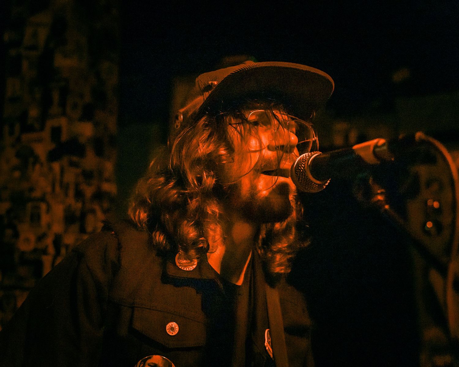 Concert performer in orange lighting singing into microphone with atmospheric effect.