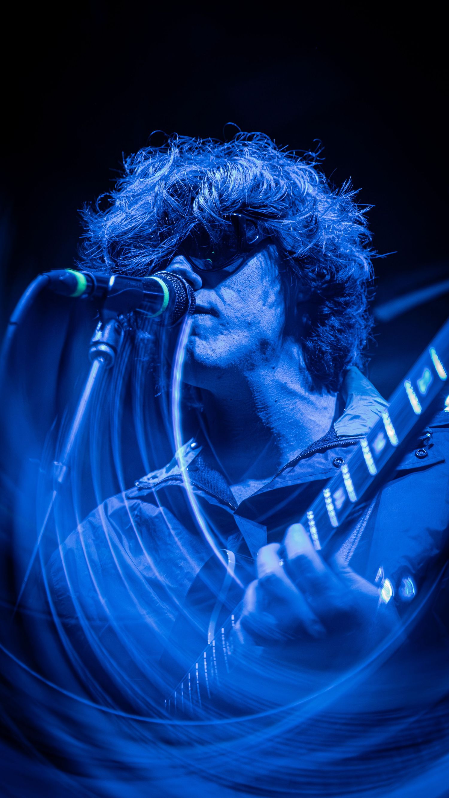 Dynamic performance shot in blue lighting with swirling motion blur effects creating an ethereal atmosphere.