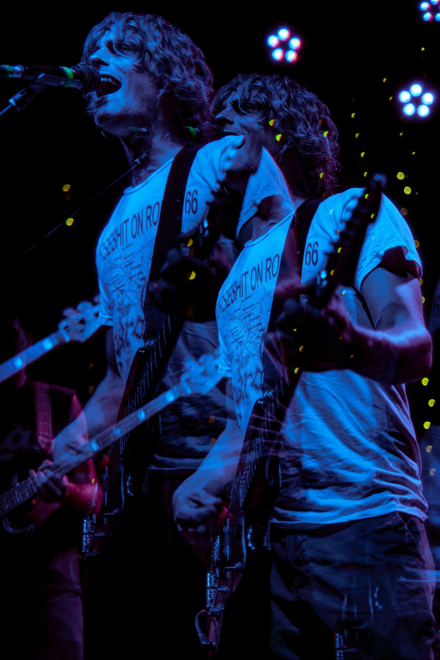 Guitarist performing on stage bathed in dramatic blue lighting during a live concert performance.