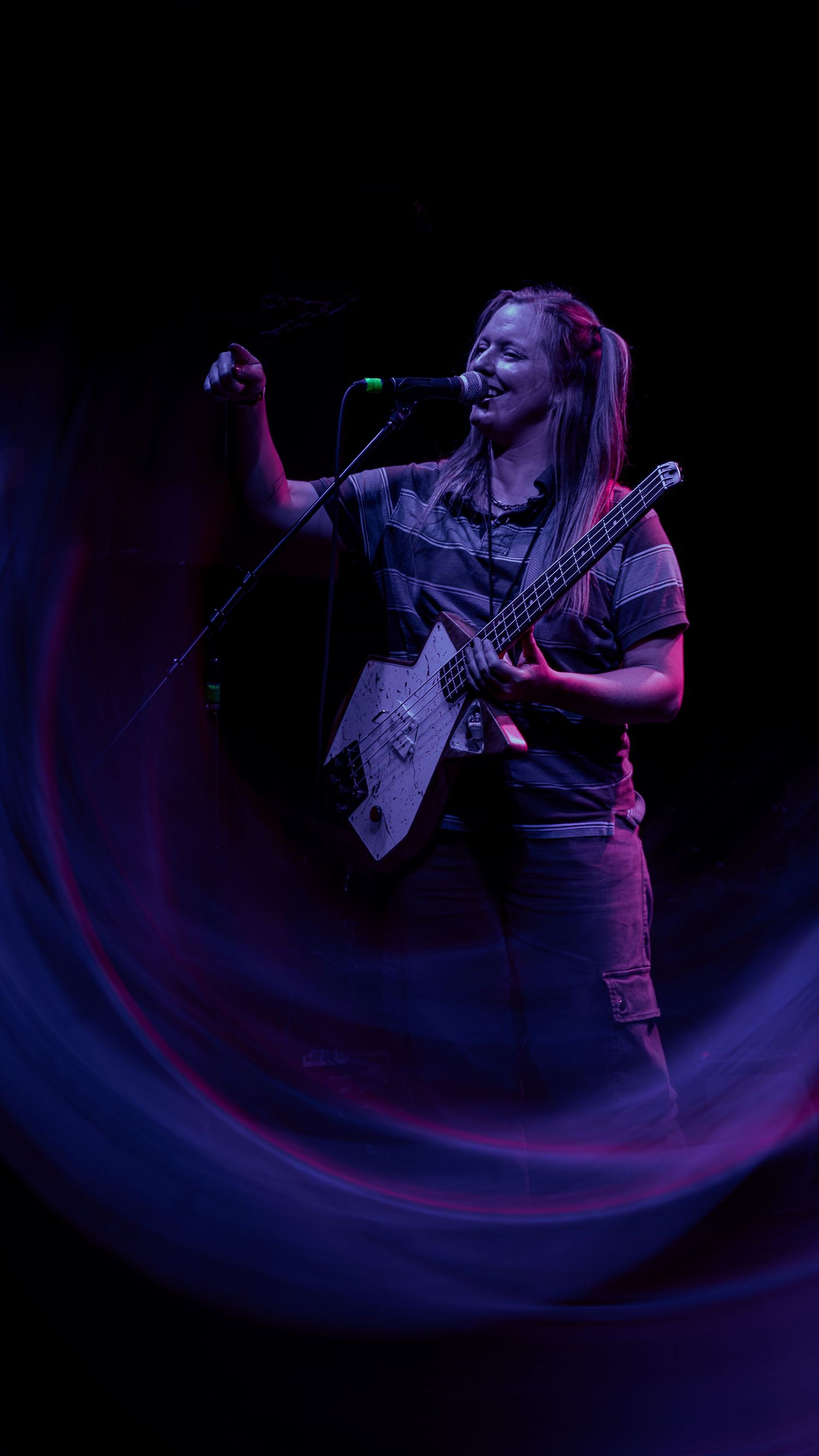 Performer singing passionately on stage in dark lighting with swirling blue effects creating dramatic atmosphere.