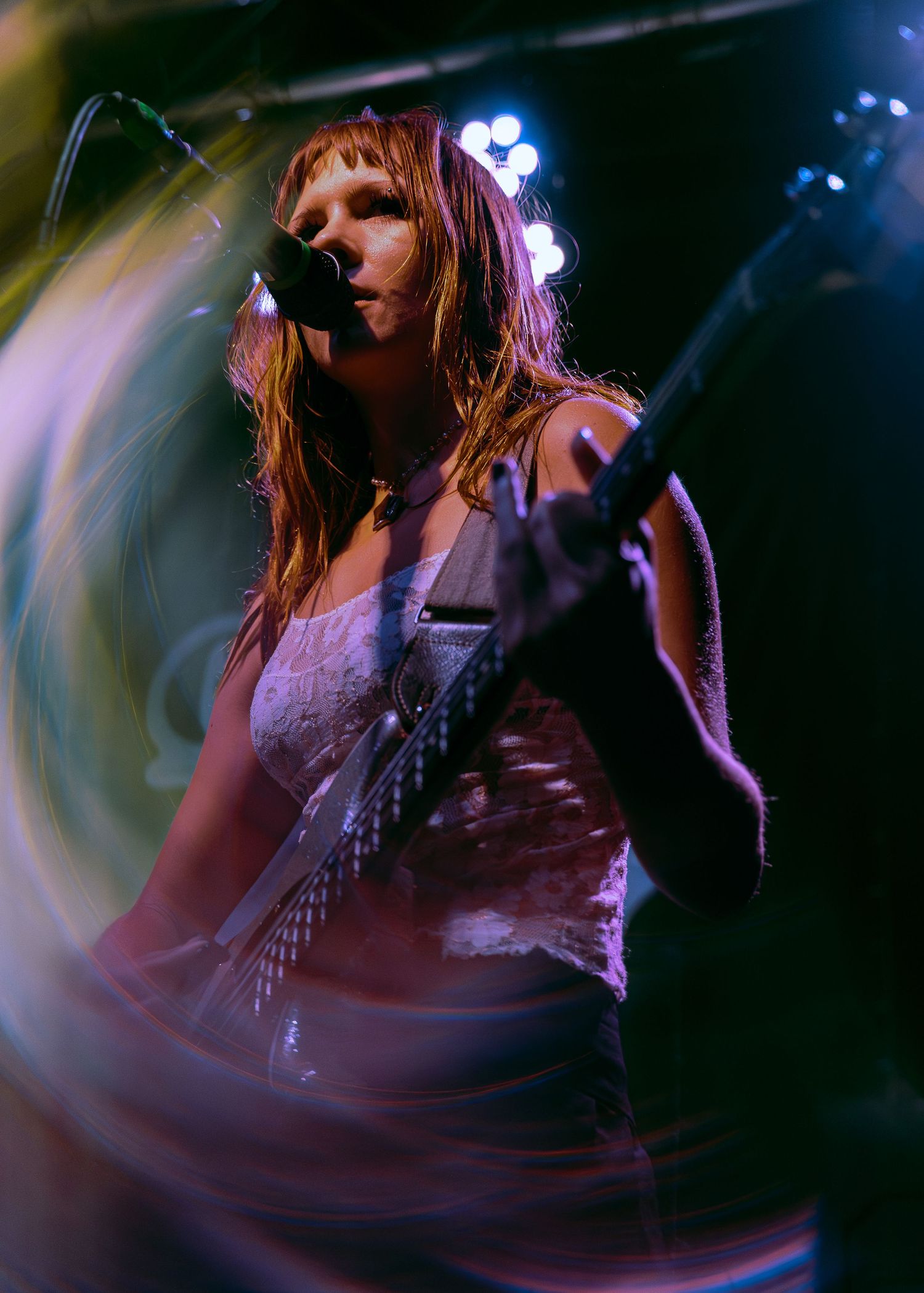 A musician performs on stage singing and playing guitar in dynamic lighting with motion blur effects.