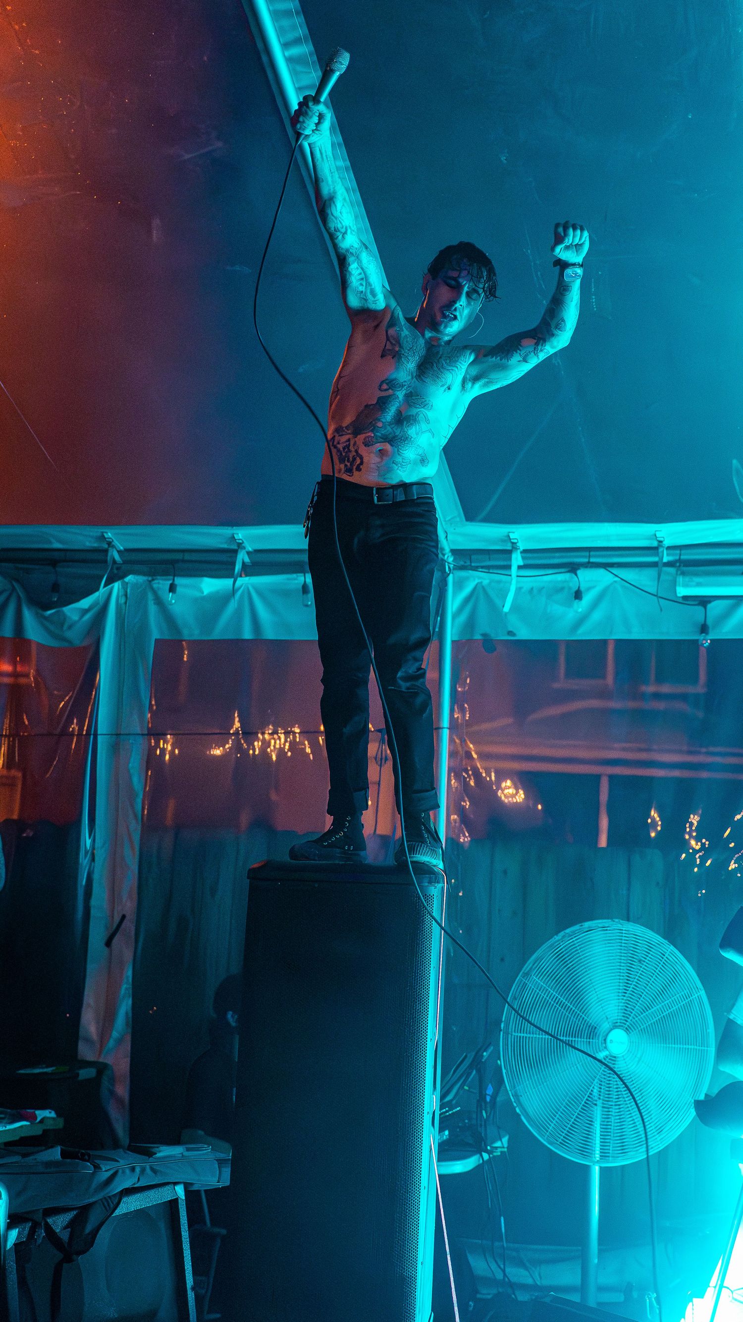 Musicians perform under striking cyan stage lights creating a moody atmospheric concert scene.