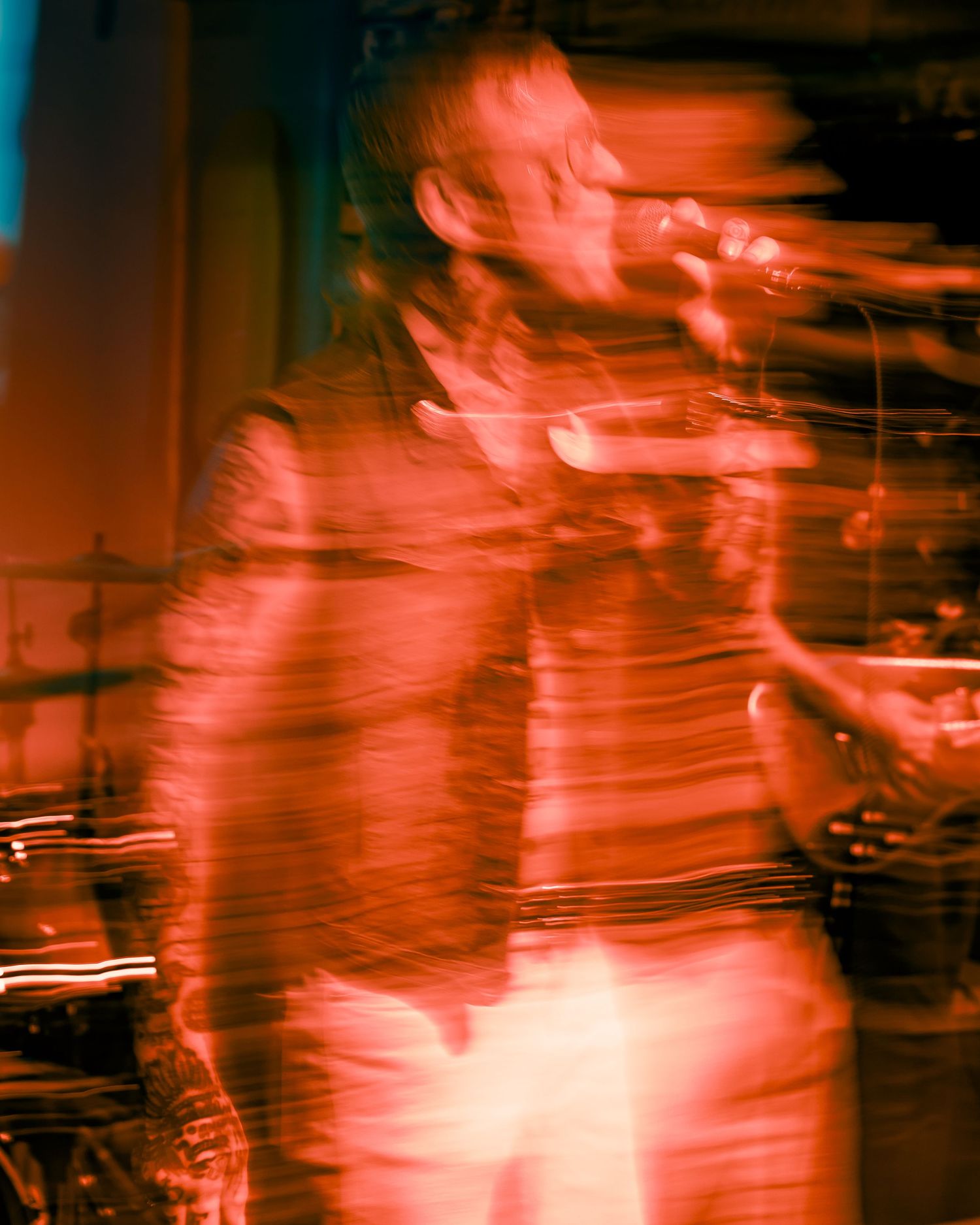 Concert performer in motion captured with red lighting and motion blur effects.